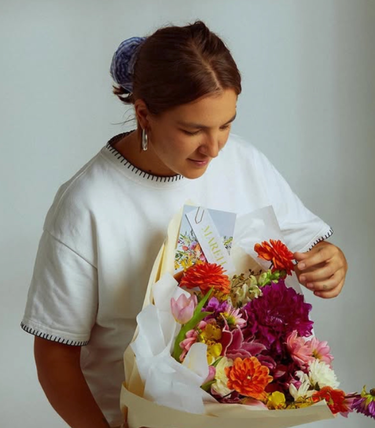 Ju, fundadora da MAREH, segurando arranjo autoral com flores da estação